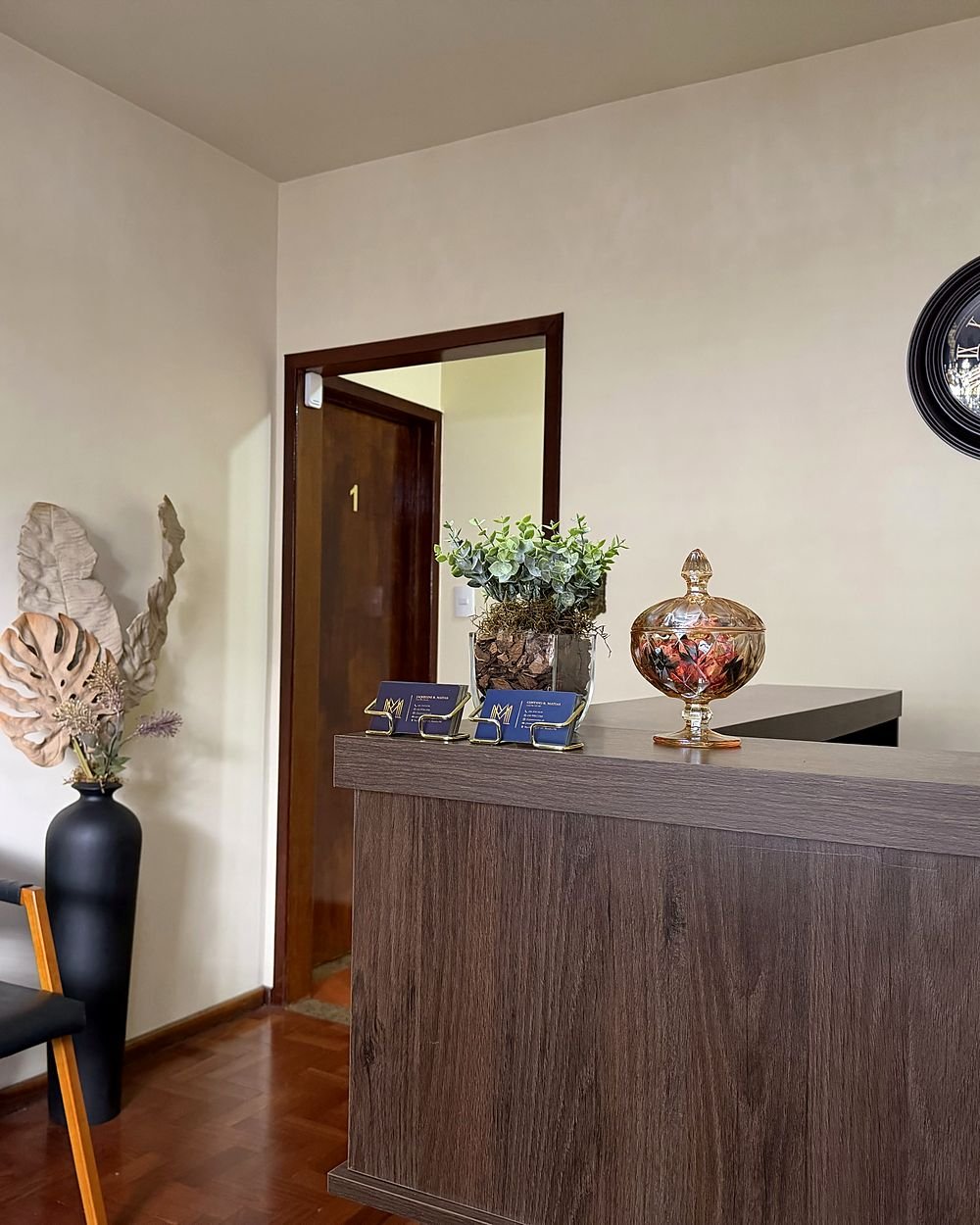Balcão de recepção com cartões dos advogados, relógio e vaso decorativo